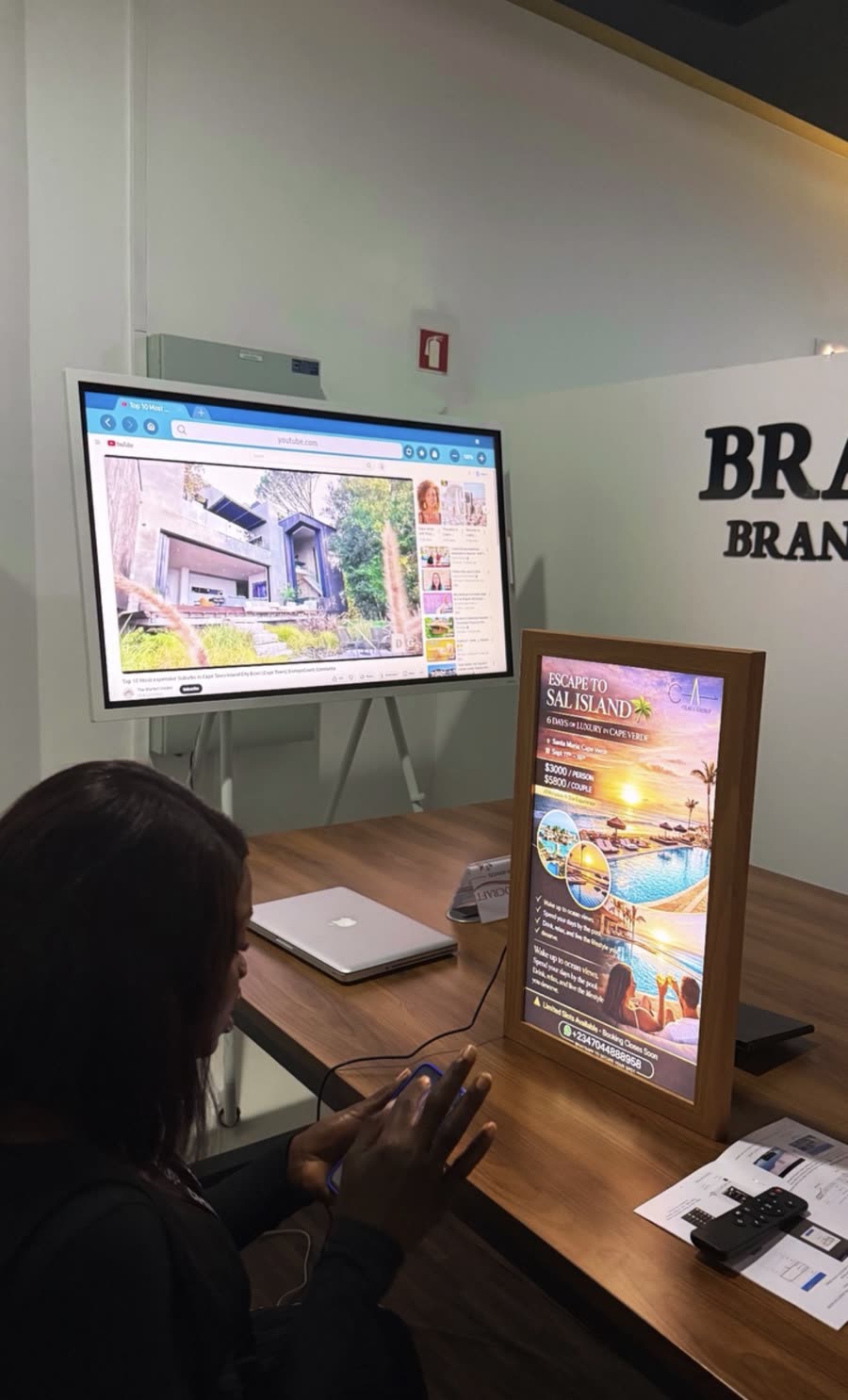 Brand Craft office with a screen and a framed Escape to Sal Island poster